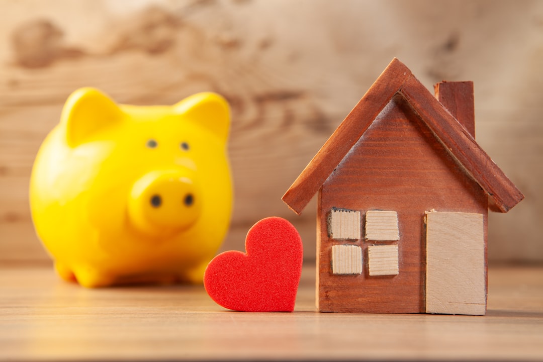Yellow piggy bank with wooden house and red heart