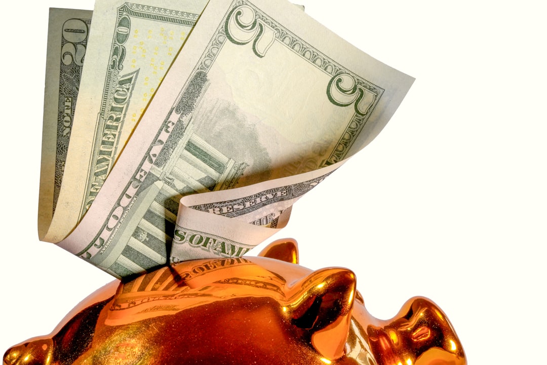 Us dollar bills being inserted into a piggy bank